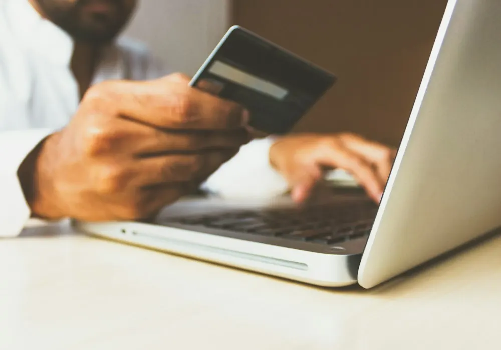 A customer shopping online with a bank card and laptop